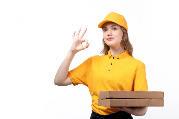 Una vista frontal joven mujer mensajero trabajadora del servicio de entrega de alimentos con cajas de entrega y sonriendo en blanco