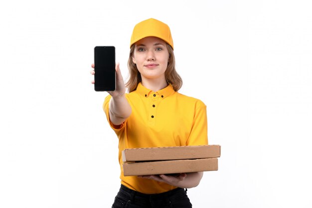 Una vista frontal joven mujer mensajero trabajadora del servicio de entrega de alimentos con cajas de pizza y teléfono inteligente en blanco