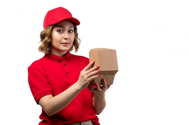 Una vista frontal joven mujer mensajero trabajadora del servicio de entrega de alimentos con paquete de alimentos en blanco