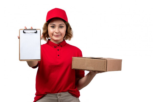 Una vista frontal joven mujer mensajero trabajadora del servicio de entrega de alimentos con paquete de alimentos y bloc de notas en blanco