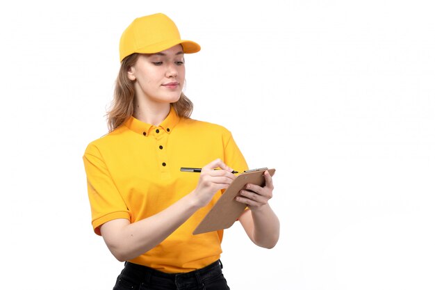Una vista frontal joven mujer mensajero trabajadora del servicio de entrega de alimentos sonriendo sosteniendo el bloc de notas escribiendo órdenes en blanco