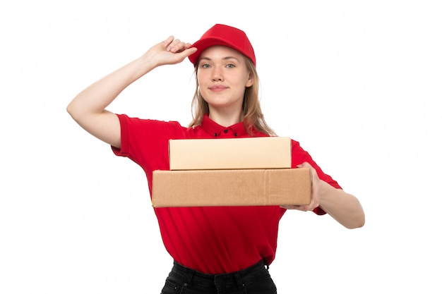 Una vista frontal joven mujer mensajero trabajadora del servicio de entrega de alimentos sonriendo sosteniendo cajas con comida en blanco