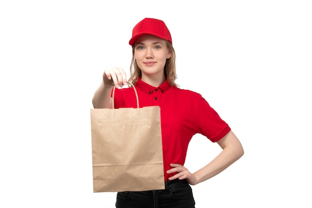 Una vista frontal joven mujer mensajero trabajadora del servicio de entrega de alimentos sonriendo sosteniendo paquetes de entrega de alimentos en blanco