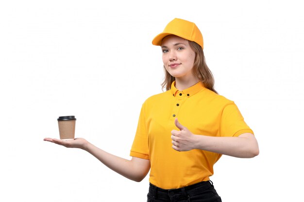 Una vista frontal joven mujer mensajero trabajadora del servicio de entrega de alimentos sonriendo sosteniendo la taza de café en blanco