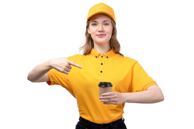 Una vista frontal joven mujer mensajero trabajadora del servicio de entrega de alimentos sonriendo sosteniendo la taza de café en blanco