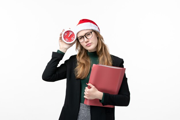 Vista frontal joven mujer sosteniendo archivos y reloj en escritorio blanco libro de navidad de año nuevo