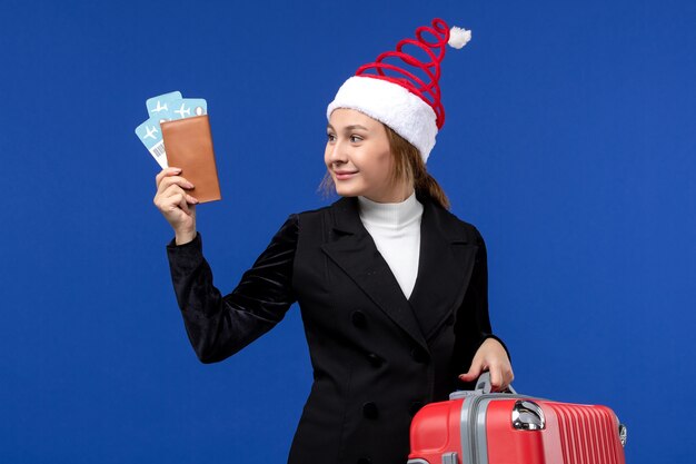 Vista frontal joven mujer sosteniendo boletos con bolsa en escritorio azul mujer vacaciones vacaciones