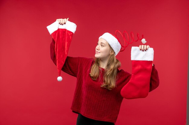 Vista frontal joven mujer sosteniendo un calcetín grande rojo y una gorra en el escritorio rojo vacaciones rojo navidad