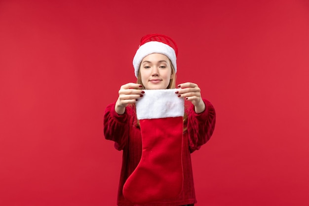 Vista frontal joven mujer sosteniendo calcetín de Navidad, vacaciones mujer roja