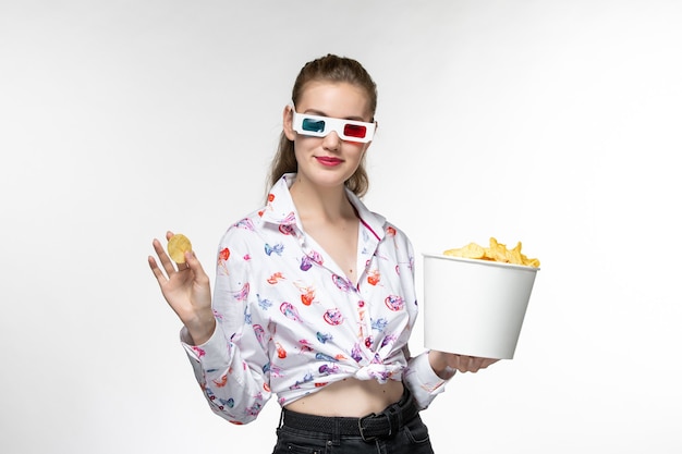 Foto gratuita vista frontal joven mujer sosteniendo la cesta con papas fritas en d gafas de sol sonriendo sobre una superficie blanca