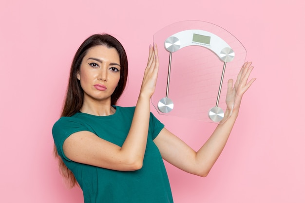 Foto gratuita vista frontal joven mujer sosteniendo escalas en la pared rosa claro ejercicio deporte entrenamiento atleta cintura belleza