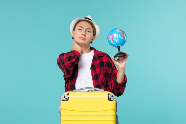 Vista frontal joven mujer sosteniendo globo terráqueo y preparándose para viaje en el espacio azul