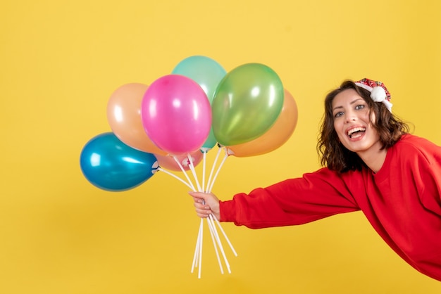 Vista frontal joven mujer sosteniendo globos en amarillo