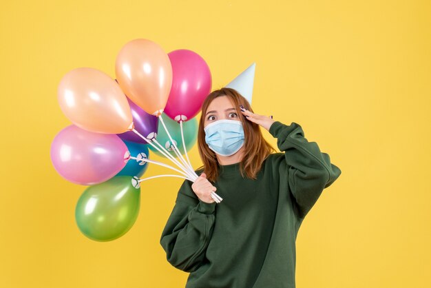 Vista frontal joven mujer sosteniendo globos de colores