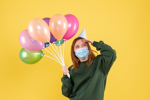 Vista frontal joven mujer sosteniendo globos de colores