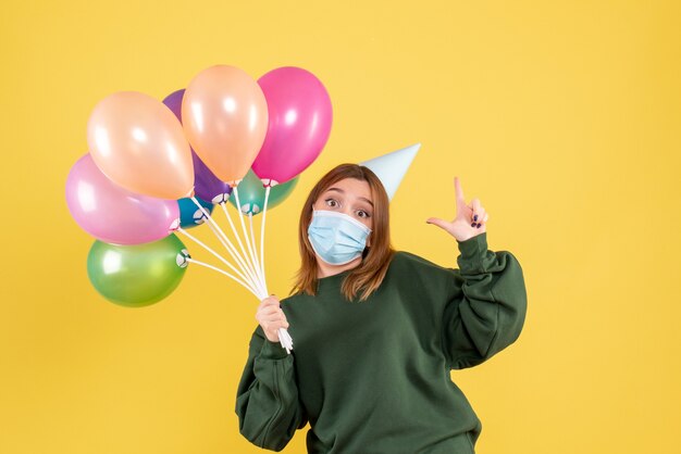 Vista frontal joven mujer sosteniendo globos de colores