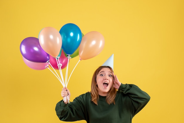 Vista frontal joven mujer sosteniendo globos de colores