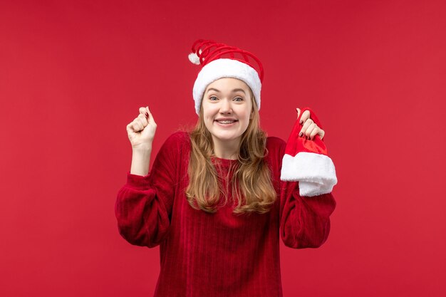 Vista frontal joven mujer sosteniendo gorro rojo, emoción de Navidad de vacaciones