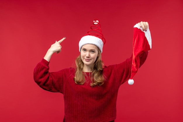 Vista frontal joven mujer sosteniendo gorro rojo, vacaciones de Navidad