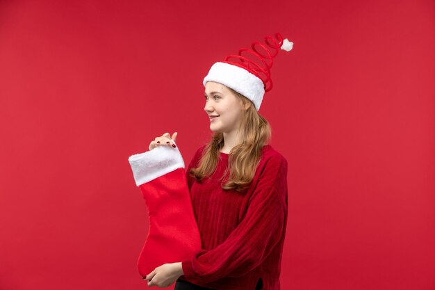 Vista frontal joven mujer sosteniendo gran calcetín de Navidad, vacaciones mujer roja