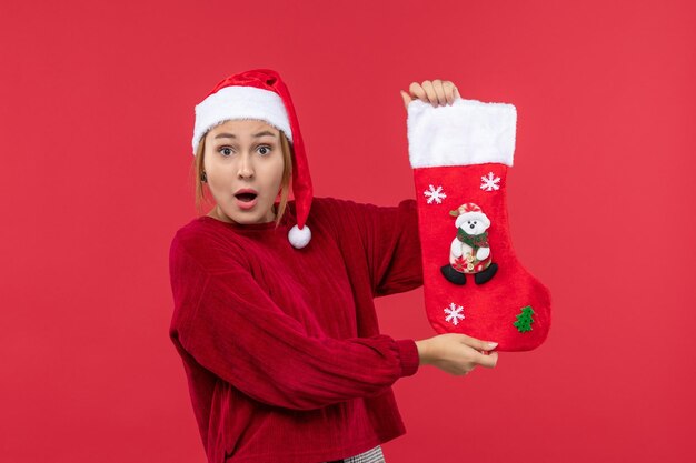 Vista frontal joven mujer sosteniendo gran calcetín navideño, vacaciones navideñas rojas