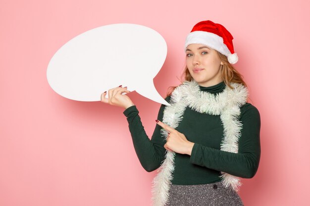 Vista frontal joven mujer sosteniendo gran cartel blanco en la pared rosa Navidad año nuevo modelo color emoción