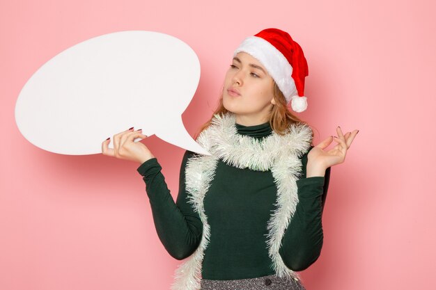 Vista frontal joven mujer sosteniendo gran cartel blanco en la pared rosa Navidad año nuevo modelo vacaciones color emoción