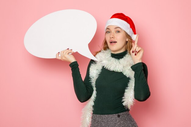 Vista frontal joven mujer sosteniendo gran cartel blanco en pared rosa Navidad año nuevo vacaciones color emoción