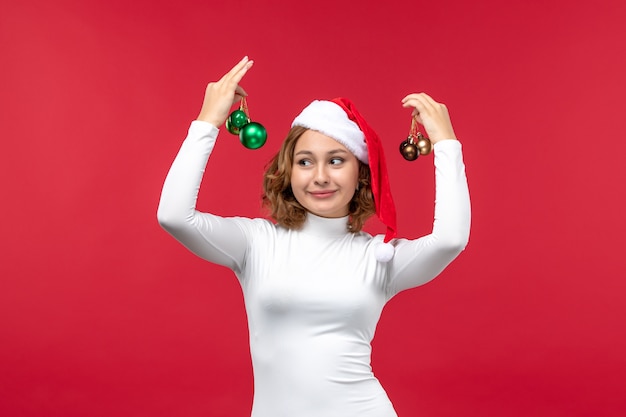 Vista frontal de la joven mujer sosteniendo juguetes de Navidad en rojo