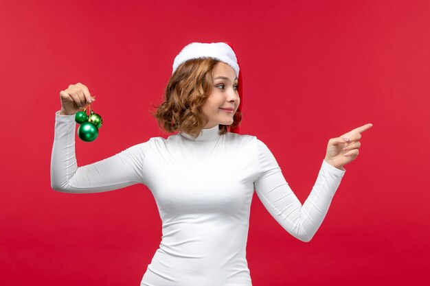 Vista frontal de la joven mujer sosteniendo juguetes de Navidad en rojo