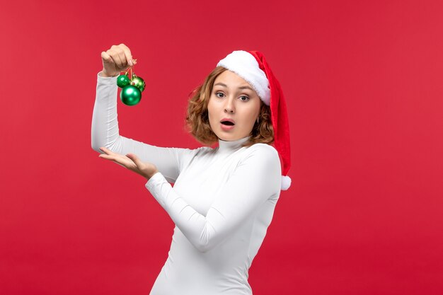 Vista frontal de la joven mujer sosteniendo juguetes de Navidad en rojo