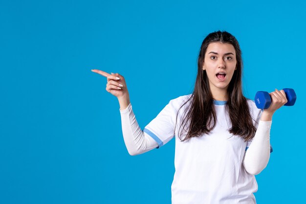 Vista frontal joven mujer sosteniendo mancuernas azul