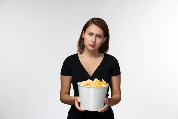 Vista frontal joven mujer sosteniendo papas fritas y viendo la película en el escritorio blanco