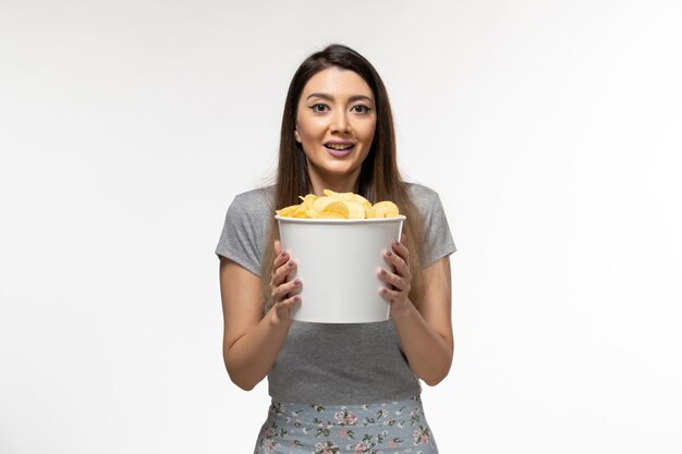 Vista frontal joven mujer sosteniendo papas fritas y viendo la película en la superficie blanca