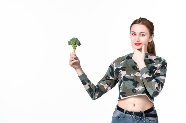 Vista frontal joven mujer sosteniendo poco brócoli verde sobre blanco