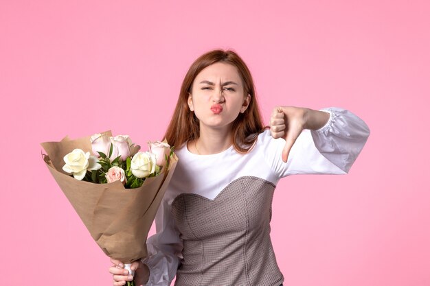 Vista frontal joven mujer sosteniendo ramo de hermosas rosas en rosas