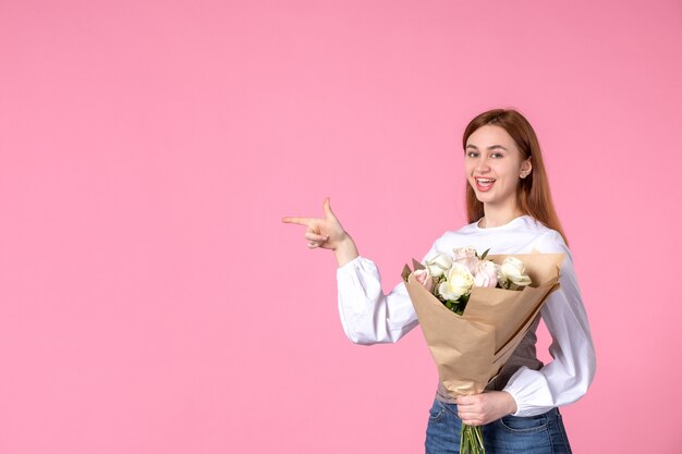 Vista frontal joven mujer sosteniendo ramo de hermosas rosas en rosas