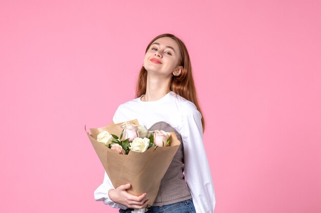 Vista frontal joven mujer sosteniendo ramo de rosas hermosas en rosa