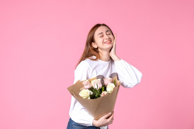 Vista frontal joven mujer sosteniendo ramo de rosas hermosas en rosa