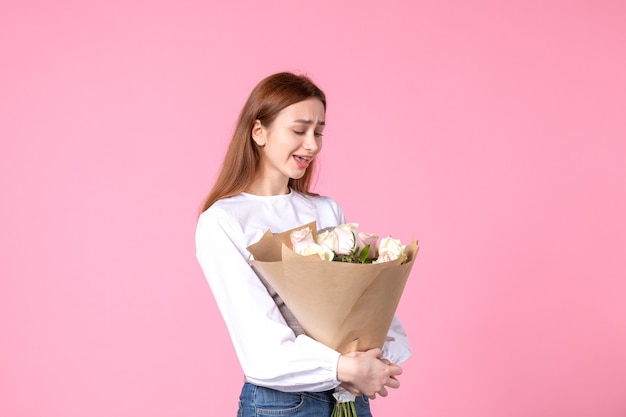 Vista frontal joven mujer sosteniendo ramo de rosas hermosas en rosa