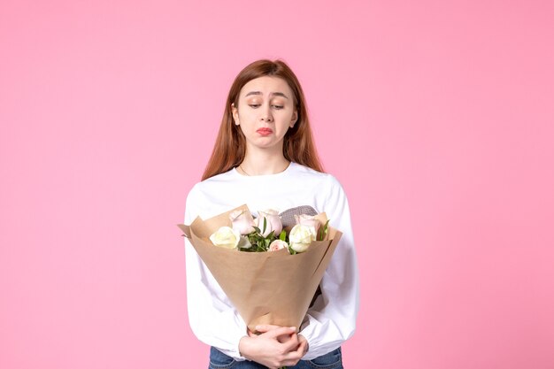 Vista frontal joven mujer sosteniendo ramo de rosas hermosas en rosa