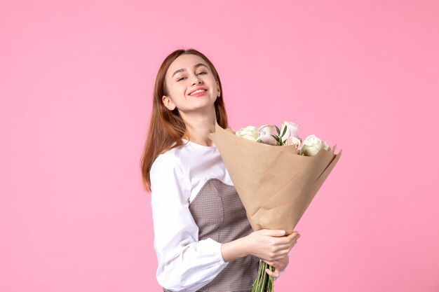 Vista frontal joven mujer sosteniendo ramo de rosas hermosas en rosa