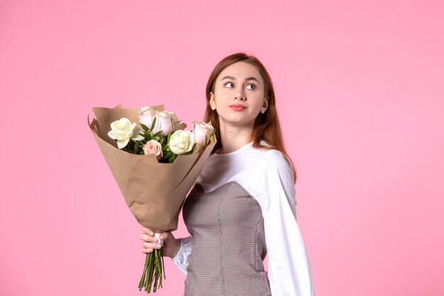 Vista frontal joven mujer sosteniendo ramo de rosas hermosas en rosa