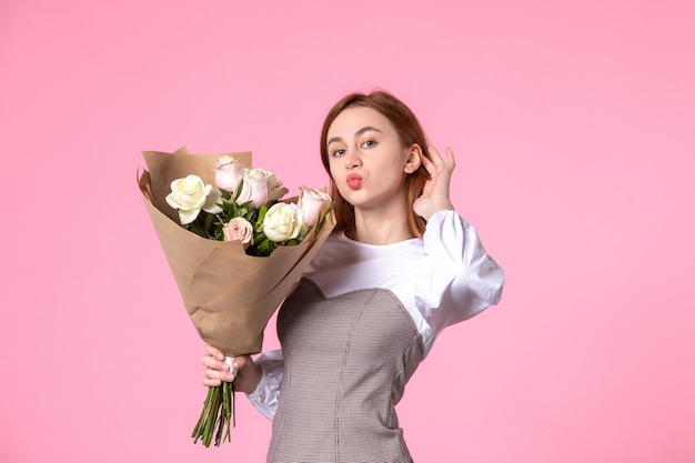 Vista frontal joven mujer sosteniendo ramo de rosas hermosas en rosa