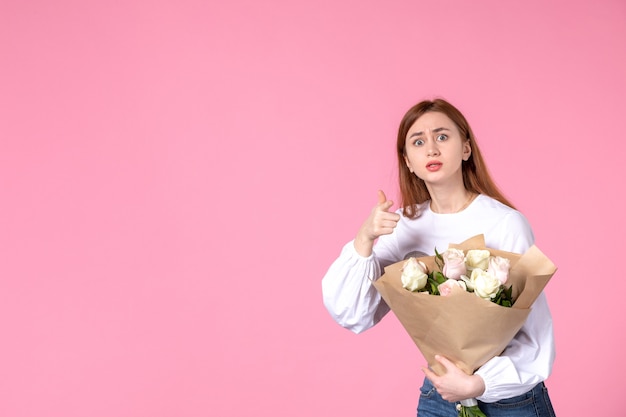 Vista frontal joven mujer sosteniendo ramo de rosas hermosas en rosa