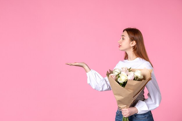 Vista frontal joven mujer sosteniendo ramo de rosas hermosas en rosa