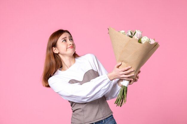 Vista frontal joven mujer sosteniendo ramo de rosas hermosas en rosa