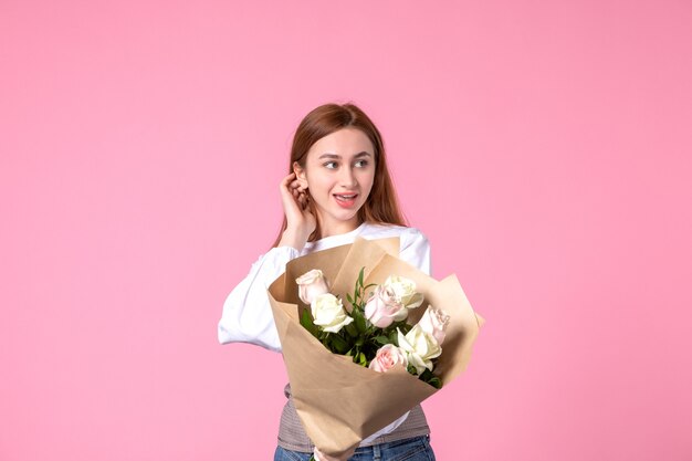 Vista frontal joven mujer sosteniendo ramo de rosas hermosas en rosa