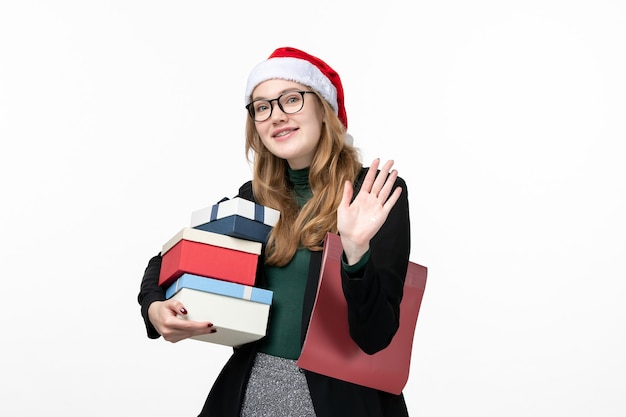 Vista frontal joven mujer sosteniendo regalos navideños en la pared blanca libro lección universidad
