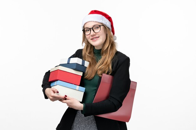 Vista frontal joven mujer sosteniendo regalos navideños en la pared blanca libro lección universidad